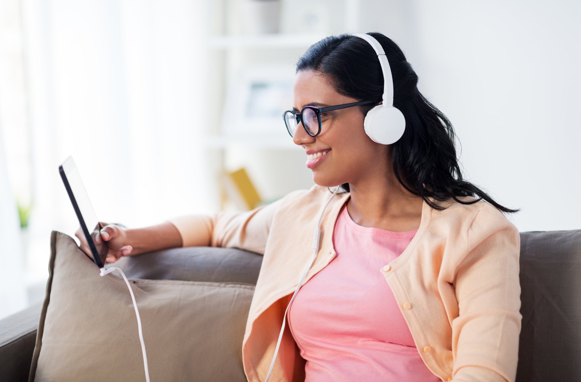 happy-woman-with-tablet-pc-and-headphones-at-home-P32QZJA-1.jpg